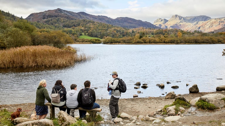 Visitors taking a break from walking by sitting on a bench at Sticklebarn and the Langdales, Lake District